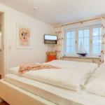 Schlafzimmer mit Doppelbett, Fenster und Vorhang. Wandbild und TV angebracht.