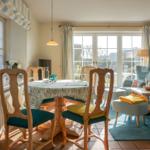 Esszimmer mit runden Tisch und Stühlen, Wohnbereich mit Sofa und Fenster.