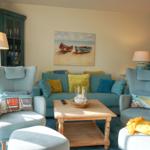 Ein Wohnzimmer mit blauem Sofa, zwei Sesseln und einem Holztisch.