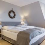 Schlafzimmer mit Doppelbett, zwei Nachttischen und Fenster. Wanddekoration mit Rettungsring.