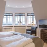 Schlafzimmer mit Blick aufs Meer, Bett, Sessel und Fernseher.