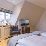 Schlafzimmer mit Doppelbett, Sessel, TV und Fenster mit Blick.