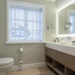 Badezimmer mit Toilette, Waschbecken und Fenster mit Jalousie.