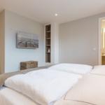 Schlafzimmer mit Doppelbett, Wandbild und Blick in das Badezimmer.