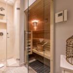 Dusche mit Regenduschkopf und Sauna mit Holzbänken und Holzwanne.