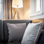Ein Sofa mit Kissen und einer Stehlampe vor einem Fenster.