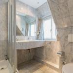 Bathroom with marble walls, shower, sink, and toilet.