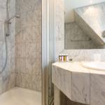 Bathroom with marble wall, shower, and sink