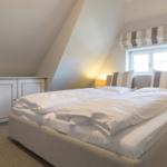 Bedroom with sloped ceiling, bed, and window with roller blind.