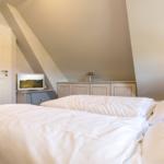 Bedroom with double bed, wardrobe, and TV under sloped ceiling.