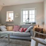 Living room with sofa, glass table, and windows.