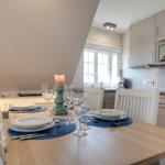 Dining table for four, kitchen area, and window in the background.