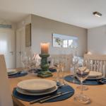 Dining room with set table, white chairs, and wall art