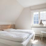 Bedroom with double bed, window, and desk.