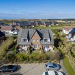 House with garden and terrace, surrounded by homes and dunes.