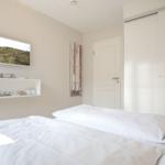 Bedroom with white bed, closet, and wall art.