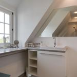 Bathroom with sink, mirror, and window. Attic with sloped ceiling.
