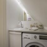 Washing machine and sink under sloped ceiling with mirror and towel.
