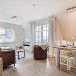 Living and dining area with wooden floor, sofa, dining table, and windows.