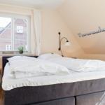 Schlafzimmer mit Doppelbett, Fenster und Wanddekoration.
