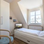 Schlafzimmer mit Dachschräge, Bett, TV und Stuhl