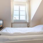Schlafzimmer mit Dachfenster, Bett und Fernseher.