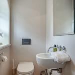 Badezimmer mit Toilette, Waschbecken und Spiegel.