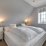 Schlafzimmer mit Doppelbett, Nachttisch und Fenster mit Segelbooten.