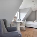 Schlafzimmer mit Dachschräge, Bett, Schreibtisch und Sessel.