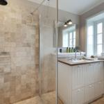 Dusche mit Duschbrause und Waschbecken mit Spiegel und Fenster