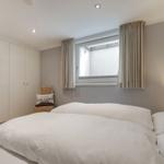 Schlafzimmer mit Doppelbett, Kleiderschrank und Fenster mit Vorhängen.