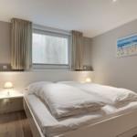 Schlafzimmer mit Doppelbett, Fenster und Wandbild.
