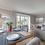 Esszimmer mit rustikalem Tisch und grauen Stühlen. Wohnbereich mit Sofa und Fernseher.