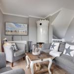 Wohnzimmer mit Sofa, Sessel, Kamin und Fernseher an der Wand.