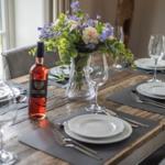 Esszimmertisch mit Platzierung, Blumenstrauß und Weinflasche.