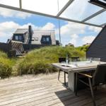 Terrace with table, chairs, and view of grass and house.