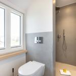 Bathroom with shower, toilet, and window with view.