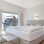 Bedroom with large bed and balcony view.