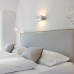 Bedroom with bed, headboard, and lamps on the wall