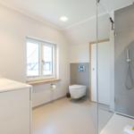 Bathroom with shower, sink, and toilet. Window with wooden windowsill.