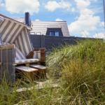 Beach chairs stand in grass in front of a house.