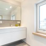 Bathroom with sink, mirror, and window with view of house.
