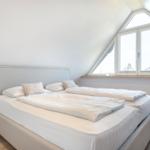 Double bed with white bedding under a skylight window.