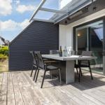 Terrace with table and chairs, modern house with glass facade and wooden deck.