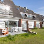 Terrace with table, chairs, and beach chair. Modern house with balcony and garden.