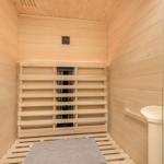 Sauna with wooden walls, benches, and floor mat.