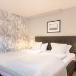 Bedroom with bed, headboard, and floral wallpaper.