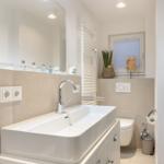 Bathroom with sink, mirror, toilet, and heated towel rail
