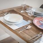 Wooden table set with dishes and place settings for guests