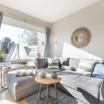 Gray sofa with cushions, round table, and mirror on the wall.